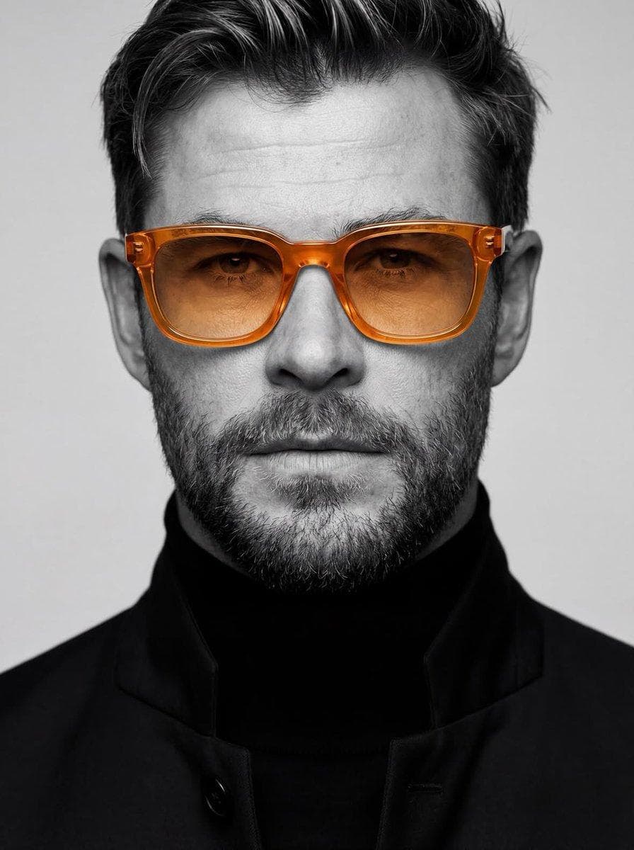 Ultra-realistic studio portrait of a man, close-up headshot, centered composition, neutral expression, sharp facial details, textured skin, clean grooming, wearing a black turtleneck and dark tailored coat, modern minimalist fashion, monochrome black and white photography style, only the glasses in color (Translucent amber-orange frame and lenses ), high contrast lighting, soft studio…
