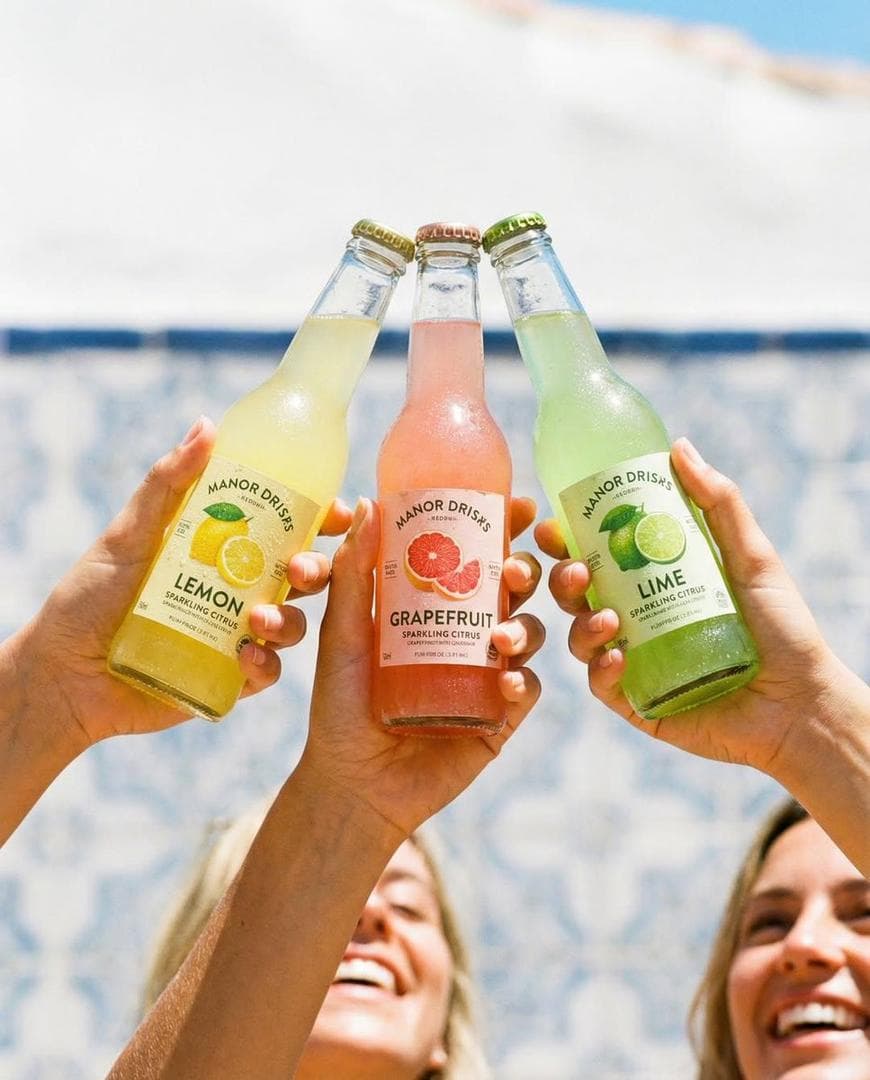 Nano Banana pro on Gemini app. Prompt: Three hands holding colorful glass soda bottles (lemon, grapefruit, lime) clinking together, bright sunny outdoor setting, soft beach/pool background blur, natural light, condensation on bottles, lifestyle photography, vibrant colors, shallow depth of field, candid joyful mood, commercial beverage ad, ultra-realistic, 8K. IMAGE 2 Three hands holding minimalist glass bottles labeled almond milk, pistachio milk, chocolate oat milk, clean neutral background, soft studio lighting, modern branding, centered composition, smooth shadows, aesthetic product photography, high detail, muted tones, premium look, 8K. IMAGE 3 Three hands holding iced coffee bottles (latte, mocha, oat milk), warm golden hour sunlight, cafe interior background, soft shadows of leaves on wall, cozy atmosphere…