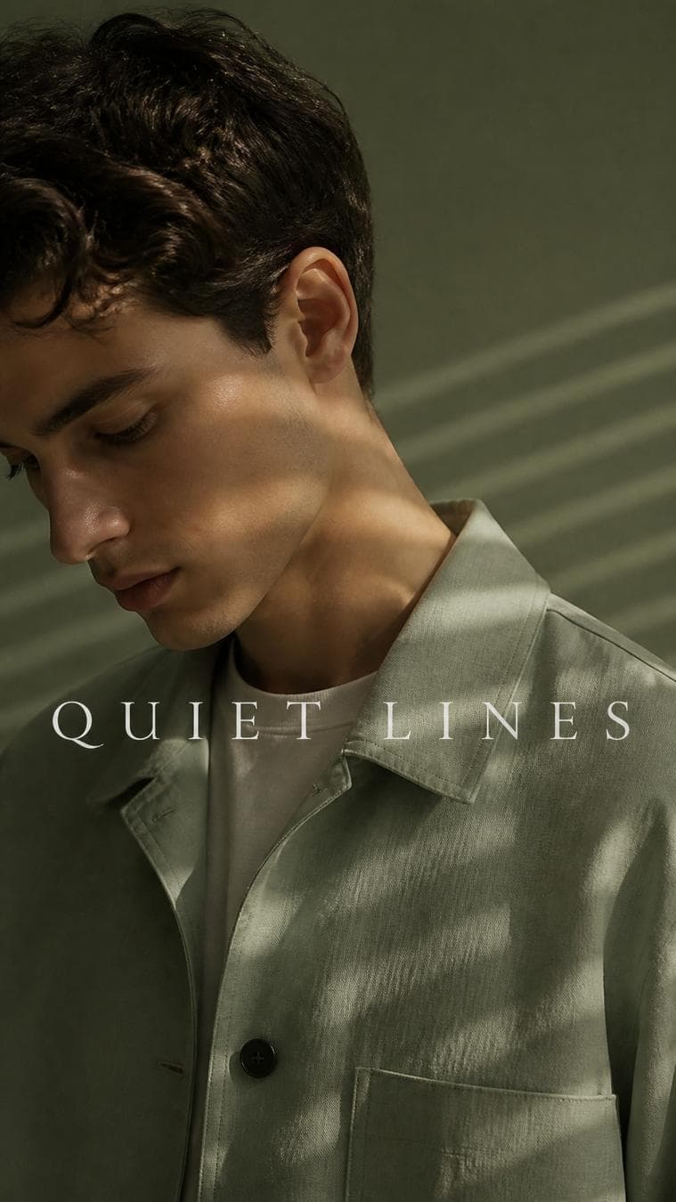 Premium minimalist campaign. Main Subject: Young male model wearing a soft sage-green overshirt. Creative Direction: Thin beams of soft light create parallel stripes across the clothing and background. Pose: Looking downward naturally…