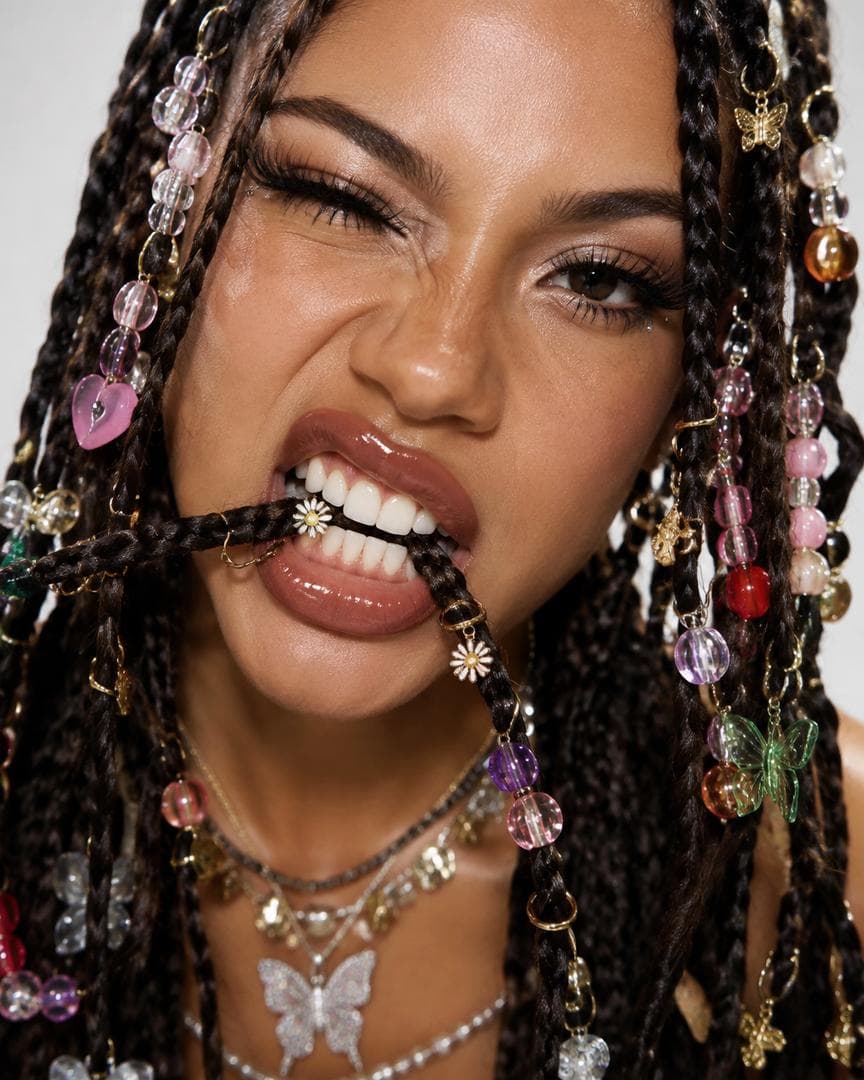 ultra realistic extreme close-up beauty portrait of a woman with multiple thin braids decorated with colorful beads, charms, tiny rings and crystals, playful rebellious expression, biting one braid between her teeth, glossy lips, dramatic lashes, high fashion editorial lighting, Y2K experimental…