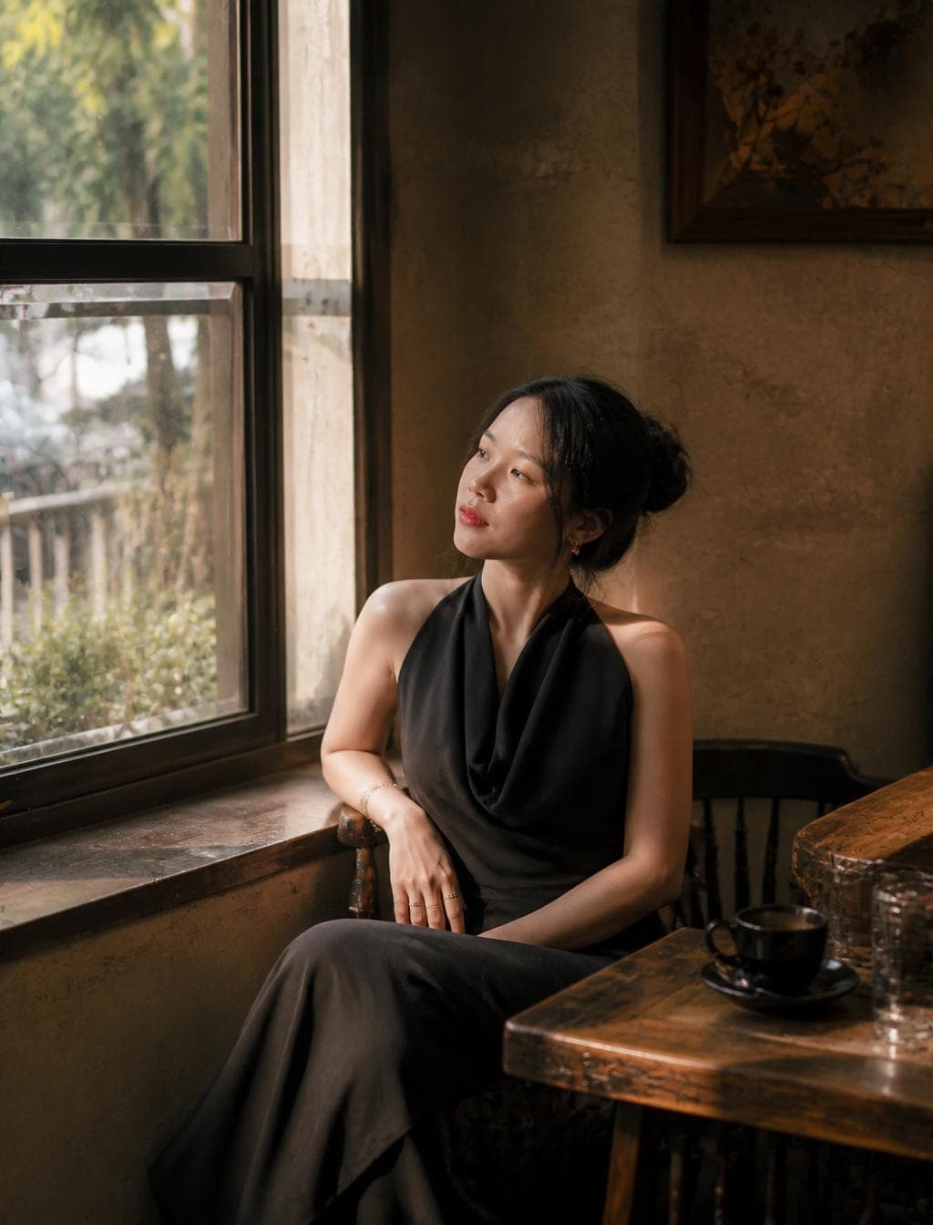 Ultra-realistic cinematic fashion photography of a beautiful woman.Wearing an elegant black designer dress with refined tailoring and luxurious fabric textures.Seated near a large window in a quiet old café.Afternoon sunlight illuminates floating dust particles.The atmosphere feels warm, nostalgic and familiar.Captured candidly while looking outside.50mm lens, shallow depth of field.Kodak Portra…