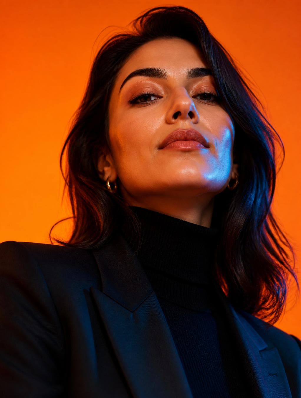 A cinematic, high-fashion editorial close-up portrait of a woman featuring the user’s face as the main subject. She wears a tailored dark blazer, and a black turtleneck. Captured from a very low angle with her chin tilted upward, she holds a direct gaze with a subtle, confident smirk. The background is a seamless, vivid orange studio…
