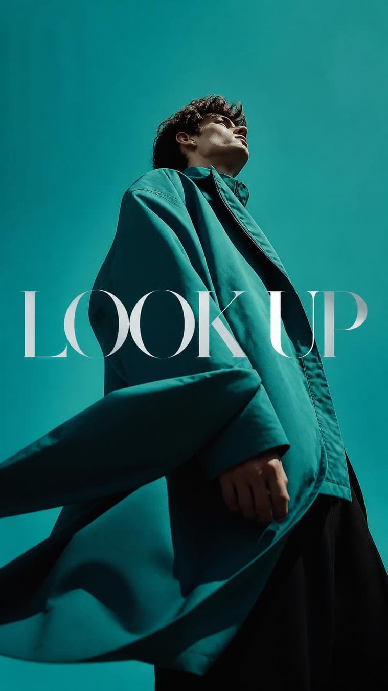 Luxury editorial campaign. Main Subject: Male model wearing teal oversized jacket. Pose: Looking upward with wind naturally moving the jacket. Camera: Extreme low angle…