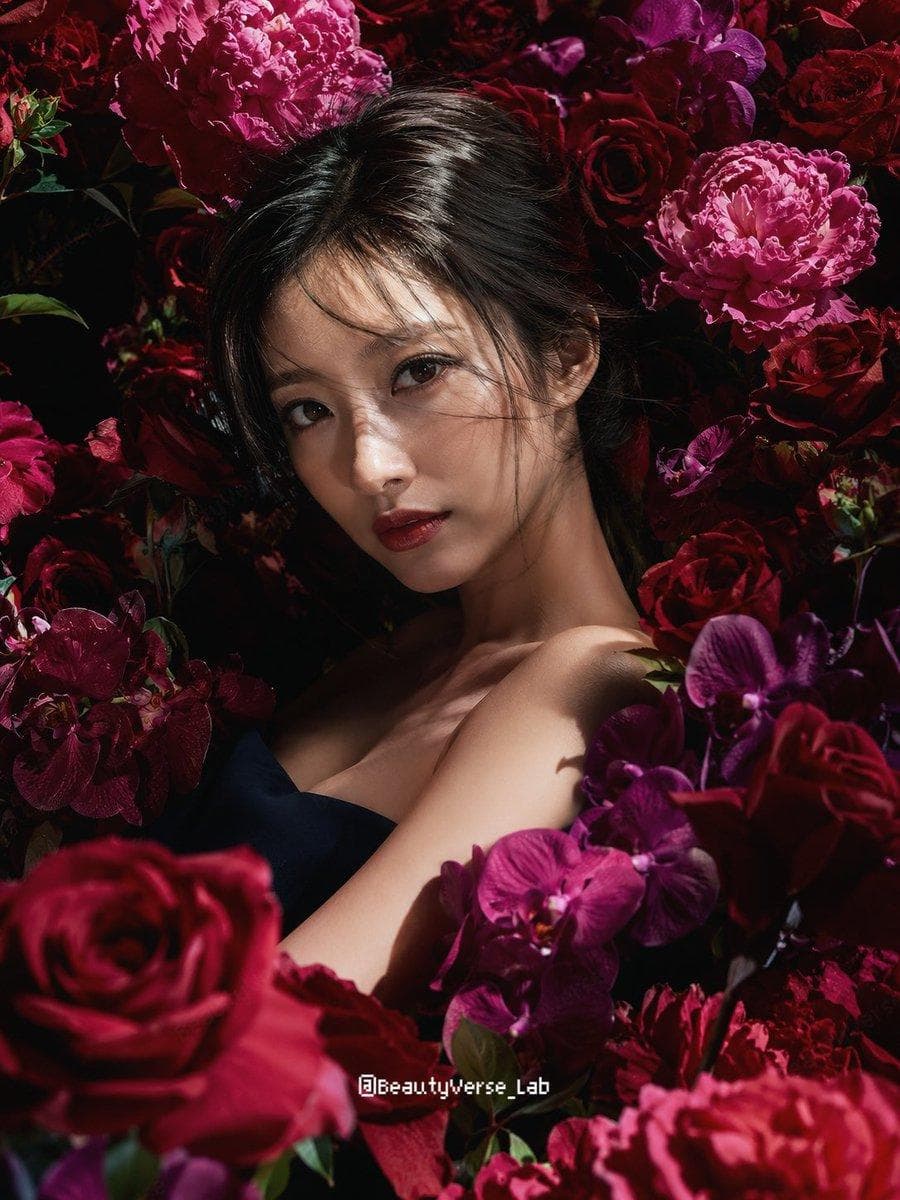[CHARACTER] Adult Japanese beauty with an exceptionally attractive appearance, refined and professional makeup, clear expressive eyes, and a captivating gaze directed straight at the camera. Realistic natural skin texture, delicate facial features, and a polished yet lifelike beauty. [Scene] She is immersed in a dense and magnificent sea of flowers, surrounded closely by layers of blooming deep red roses, rich dark purple orchids, and vivid pink peonies. The flowers fill the frame from foreground to background, creating an overwhelming floral environment with lush volume and dramatic natural density. [Lens] Upper body candid portrait with a realistic photography look, using a portrait lens perspective and shallow depth of field to emphasize the face while preserving rich floral detail around the subject. [Composition] Upper body snapshot composition, direct eye contact with the camera, the subject framed tightly within the floral surroundings. Flowers encircle her from all sides, partially overlapping around the shoulders and edges of the frame, creating a visually immersive and luxurious portrait. [Atmosphere] Dramatic, romantic, cinematic, intense, and visually striking. The image carries strong emotional tension and a glamorous editorial mood, with a sense of being enveloped by nature’s beauty and richness. [Color Palette] Deep crimson red, dark purple, vivid pink, natural skin tones, and rich shadow tones. Strong contrast between…