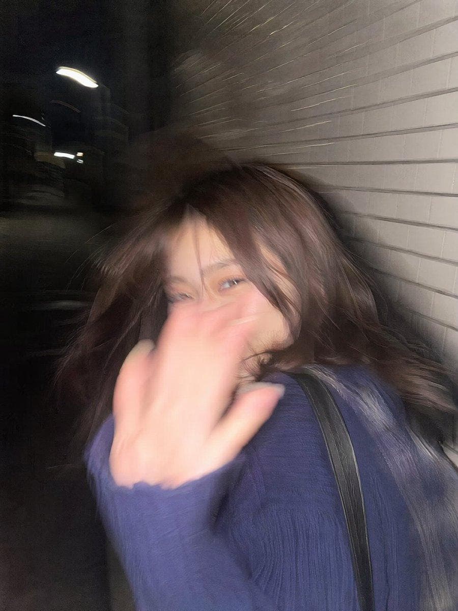 { "prompt": "Ultra-realistic candid smartphone photo, 3:4 vertical. Original non-identifiable young woman inspired only by general proportions/vibe. Night Tokyo sidewalk beside white ceramic tile wall. Mid-walk, half-profile, turning back in surprise, hand raised toward lens, shy restrained smile, continuing forward, imperfect framing, nearly exiting frame. Flash fired during motion. Strong handheld shake, heavy directional blur, smeared facial details, blurred hand and hair, ghosting, streaked tile wall, deep darkness around. Harsh flash highlights, blown exposure, hard shadows. Raw accidental snapshot, intrusive, playful, fleeting memory. Extremely noisy, heavily blurred, authentic…
