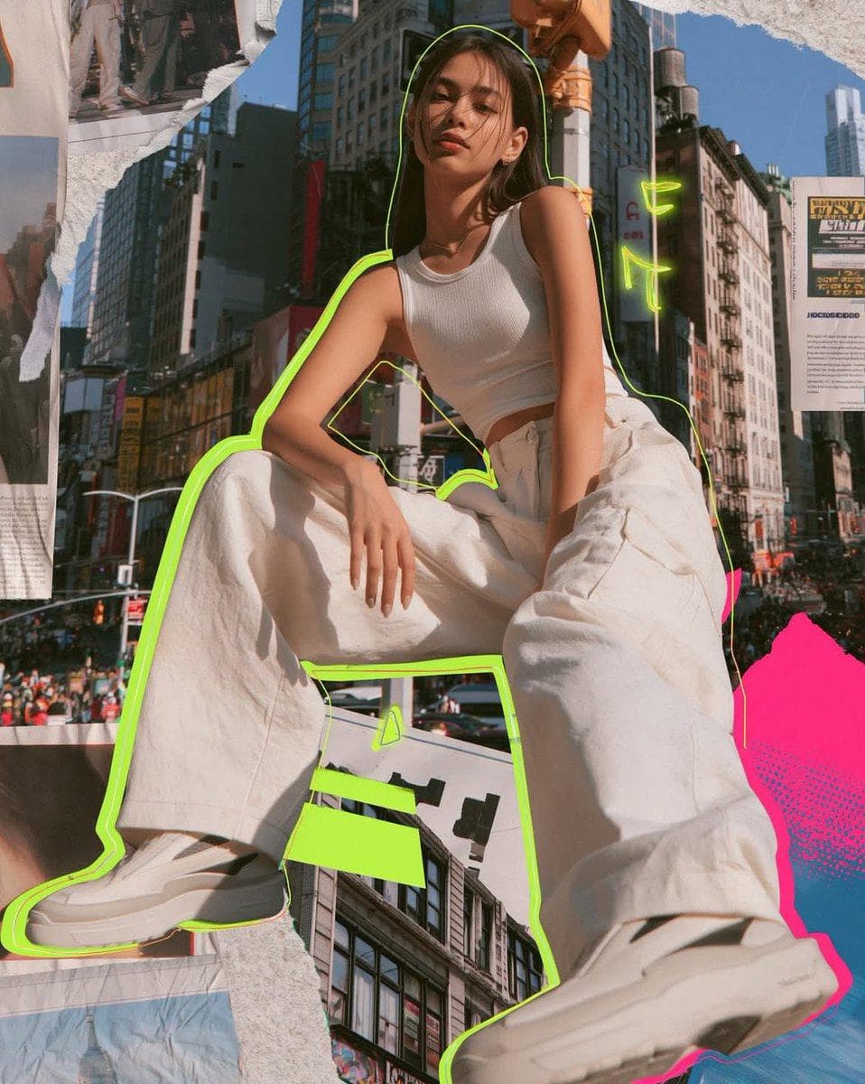 Photorealistic mixed media fashion collage of a cool young woman in a modern urban setting. Shot slightly below, straight on or soft 3/4 body composition. Confident cool girl presence wearing relaxed wide leg trousers, fitted cropped tank, and sleek streamlined sneakers. Full color, natural skin tones, dark hair, polished fashion editorial look. Colorful New York style background: tall buildings, busy street energy, layered architecture, vibrant yet clean and editorial. Mixed media collage elements throughout: torn paper textures, editorial paper layers, subtle halftone details, graphic shapes. Vivid neon accents acid lime green and hot pink with high saturation. Thin but clearly visible neon outline…
