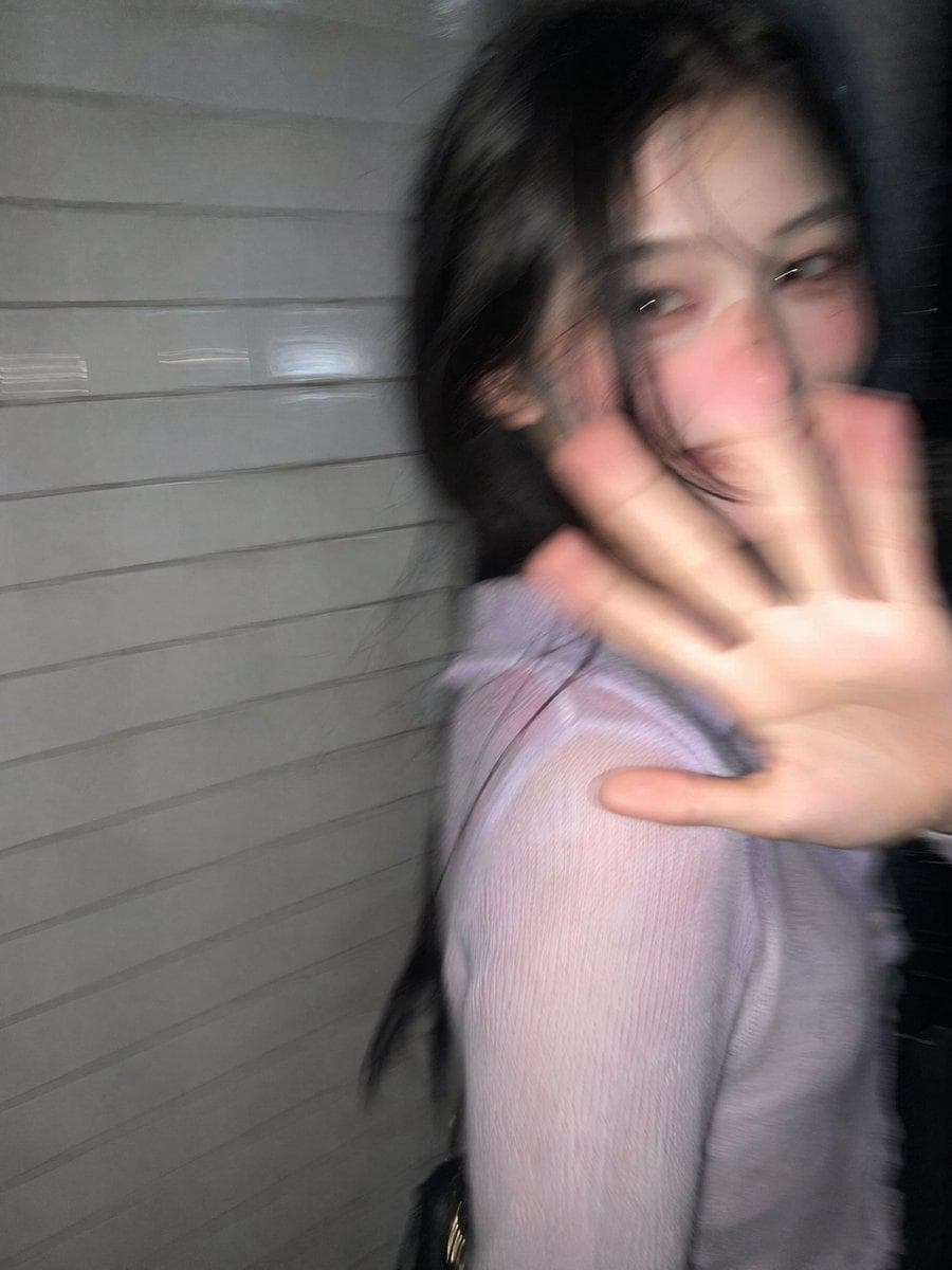 { "prompt": "Ultra-realistic candid smartphone snapshot in 3:4 vertical format. Completely generic, non-identifiable young woman based only on typical proportions and overall impression. Nighttime Tokyo sidewalk right beside a white ceramic tile wall. Captured mid-stride in three-quarter profile, head whipping back in surprise, one hand raised toward the lens, shy controlled smile, body still moving forward. Loose imperfect framing, subject nearly walking out of shot. Flash triggered while in motion. Strong handheld shake with heavy directional motion blur, facial details smeared, hand and hair softened by blur, ghosting artifacts, streaked tile wall, deep darkness surrounding the figure. Harsh flash creating bright blown highlights and sharp dark shadows. Feels like a raw accidental phone photo — intrusive, playful, fleeting…